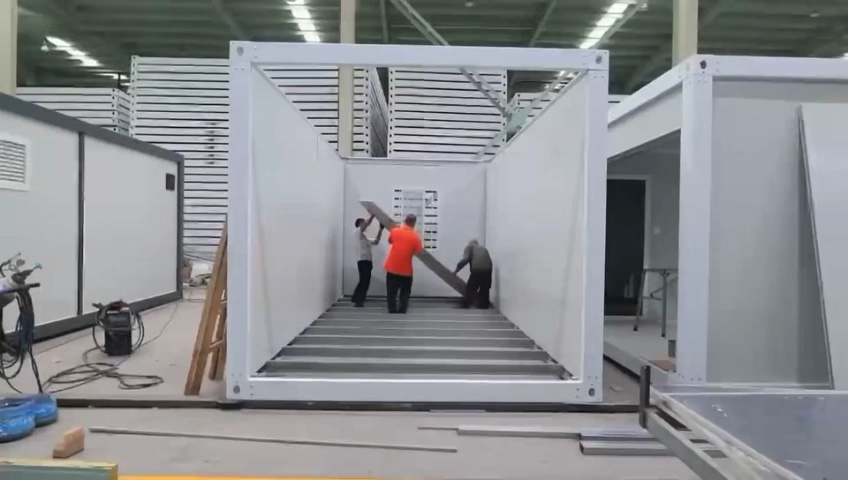 Supplier factory demonstration showing workers assembling a modular unit frame and wall panels